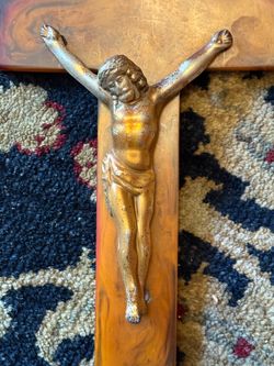 This vintage crucifix features a brass-colored figure of Jesus mounted on a warm-toned, marbled bakelite cross