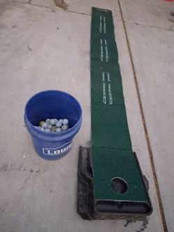 Bucket of golf balls and golf putting green