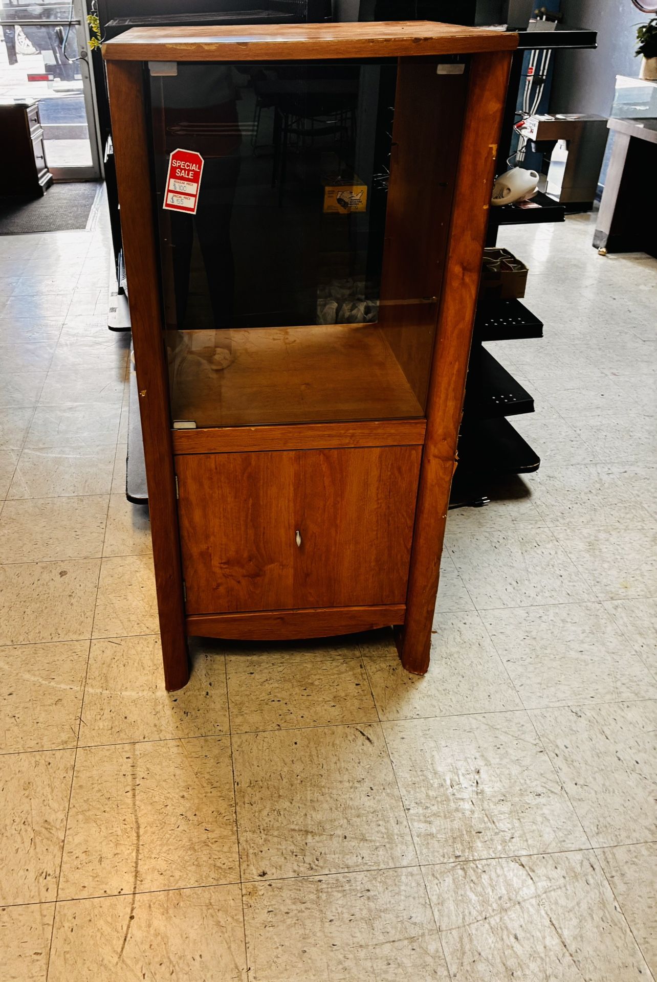 Description: Mid-century style wooden display cabinet featuring a glass front and side panels for clear viewing.
