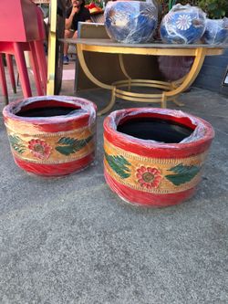 Two hand-carved and hand-painted terracotta flowerpots featuring a floral design and decorative borders in shades of red, yellow, and green.