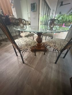 Beautiful, solid wood and wrought iron carved upholstered chairs with 60 inch glass etched round table with pedestal.