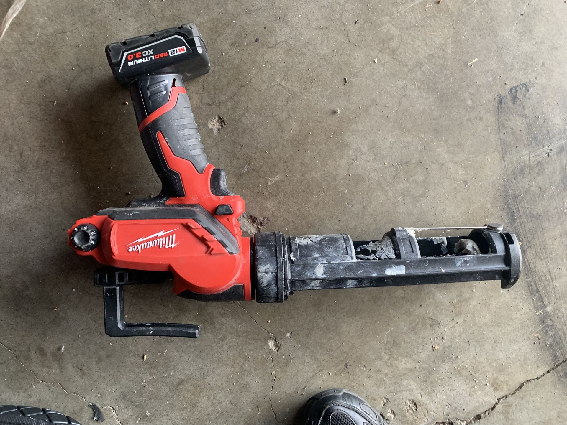 Milwaukee M12 Cordless Caulk and Adhesive Gun, powered by a Milwaukee M12 REDLITHIUM XC3.0 battery.