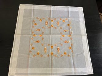 Beautiful vintage hand-embroidered table topper featuring orange, gold, and cream floral embroidery on a sheer white 100% cotton fabric.