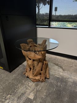 Natural wood, teak root side/accent table with a round glass top.