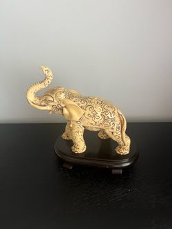 Blonde elephant with art designs on wood stand