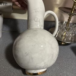  Nice Anthropologie white ceramic pitcher or vase with handle. Has a marbled design.  Gold colored trim around base. Measures 11 inches tall.