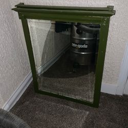 item pictured appears to be a wall-mounted mirror with a dark green painted wooden frame, similar in style to vintage medicine cabinets or decorative