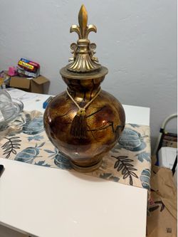 Beautiful decorative glass urn/vase, featuring an amber and bronze-toned swirl pattern with a fleur-de-lis finial,