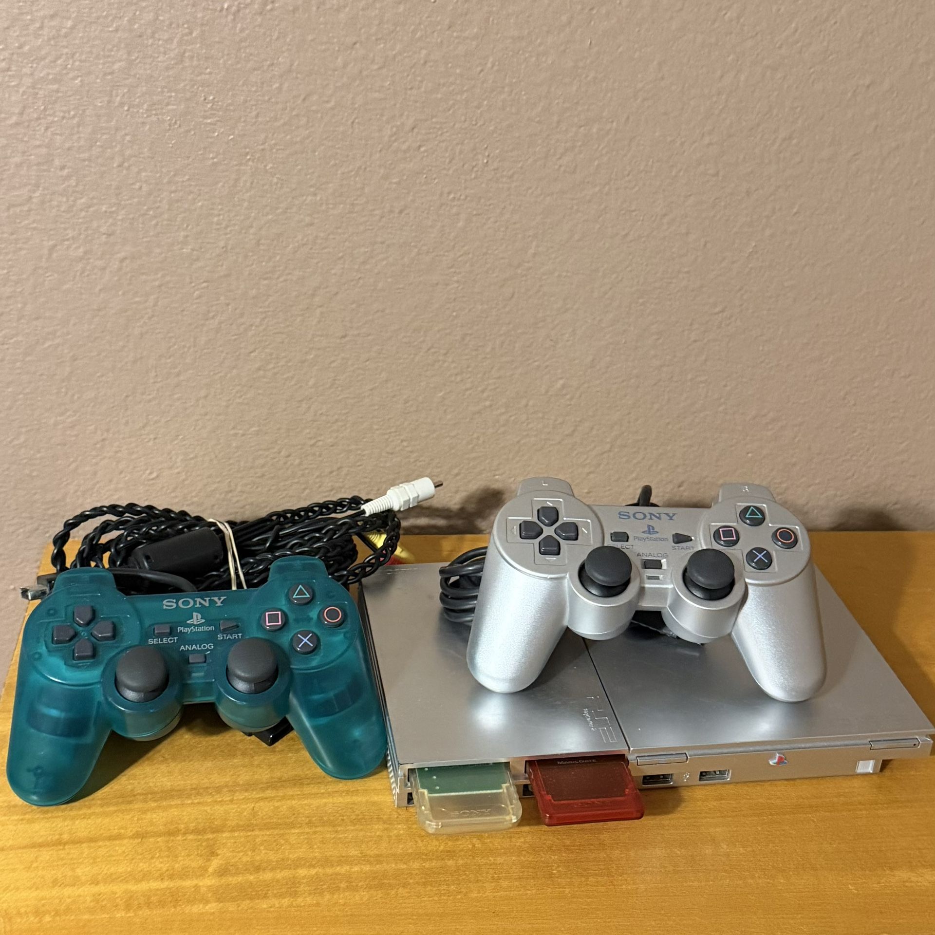 Silver Playstation 2 + Emerald green controller + 2 memory cards + PS2 media remote 