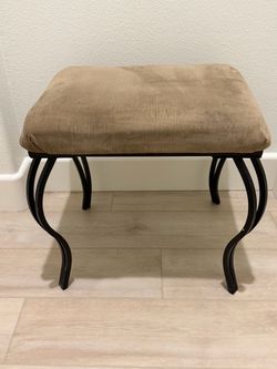Tan Upholstered Vaniy Stool with black metal legs. 19”L x 16” W x 18” H