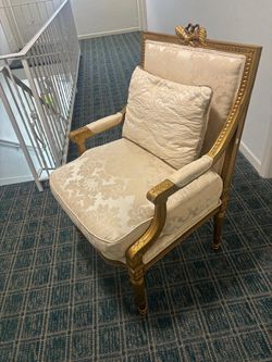 Vintage antique Louis XVI-style giltwood fauteuil armchair featuring carved gilded wood, a ribbon carving on the crest rail, and light-colored damask 