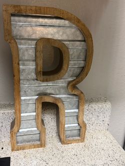 Decorative letter “R” featuring a rustic wood border