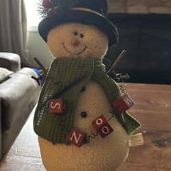 Plush snowman holding block letters