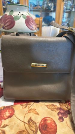 This beige Rosetti crossbody bag features a gold-toned brand plaque on the front flap