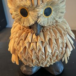 This is a handmade owl sculpture crafted from natural materials, specifically wood chips or bark.