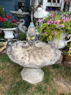 Vintage concrete birdbath with garden gnome