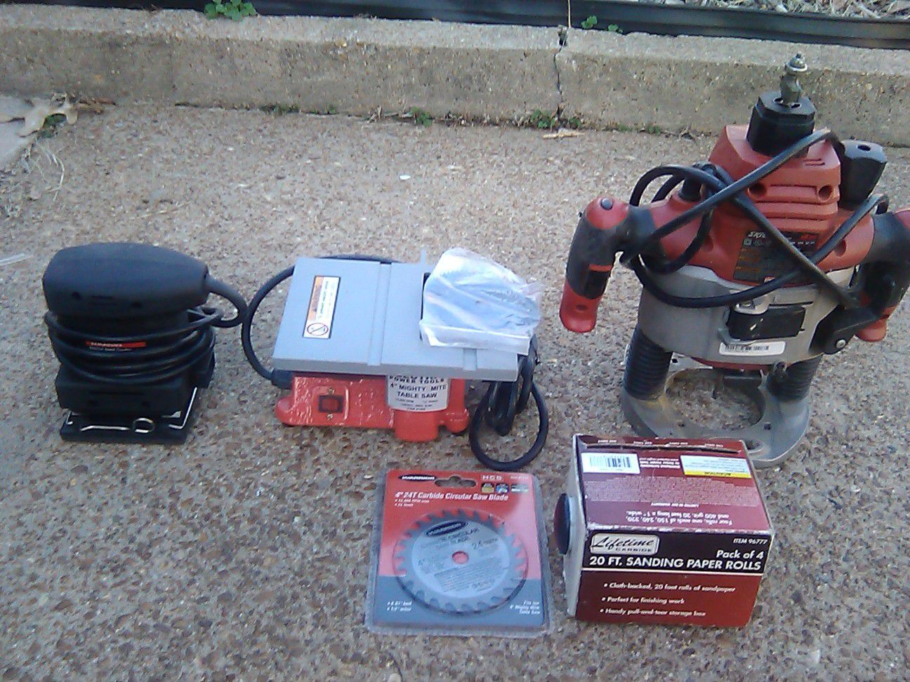 Assorted power tools, saw blades. router, 1 bullnose cuter and 1 inch sandpaper. A mini saw table