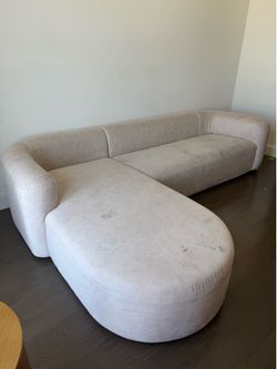 modern curved sectional sofa with a left-facing chaise in a cream/off-white
