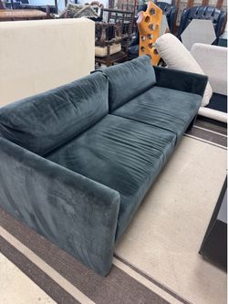 sofa features a deep teal velvet upholstery