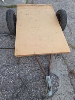 small homemade flatbed utility trailer with a wooden deck & two pneumatic tires