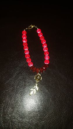 Red bracelet with gold leaf charm