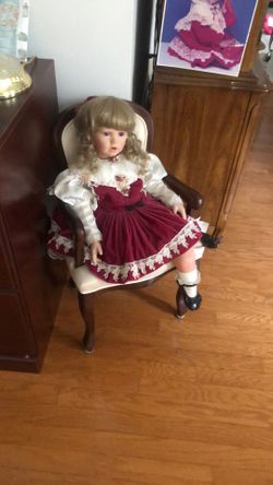 Porcelain doll In vintage chair