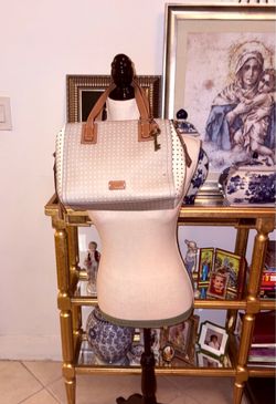 The Fossil Emma Satchel bag in white and gray with a polka dot print and brown leather handles stands out for its classic key charm.