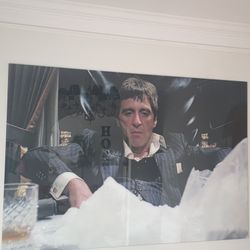 The image is a picture of a framed print featuring actor Al Pacino as the character Tony Montana from the 1983 film Scarface. 