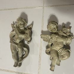pair of vintage-style resin cherub musician wall sculptures.  The set includes two cherubs, one playing what appears to be a harp or lyre and the othe