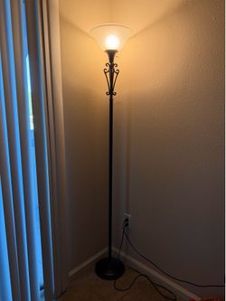 Elegant floor lamp with a decorative metal design and frosted glass shade