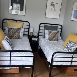 2 Black Frame twin beds with mattress and bedding.