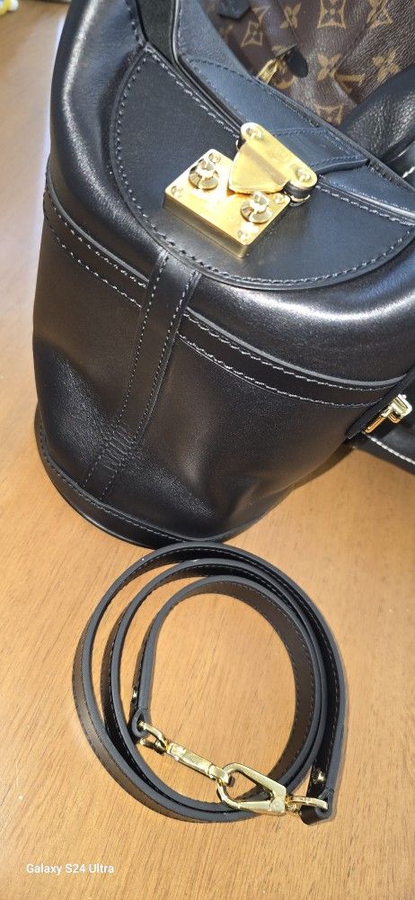 This is a Louis Vuitton Calfskin Duffle Bag in black leather with gold-tone hardware. 