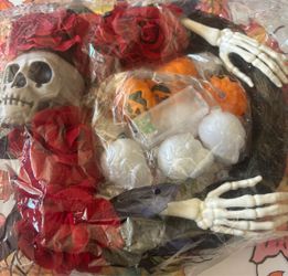 Halloween decoration set featuring a skull, red artificial roses, skeletal hands, and light-up pumpkin and ghost string lights, similar to a Halloween