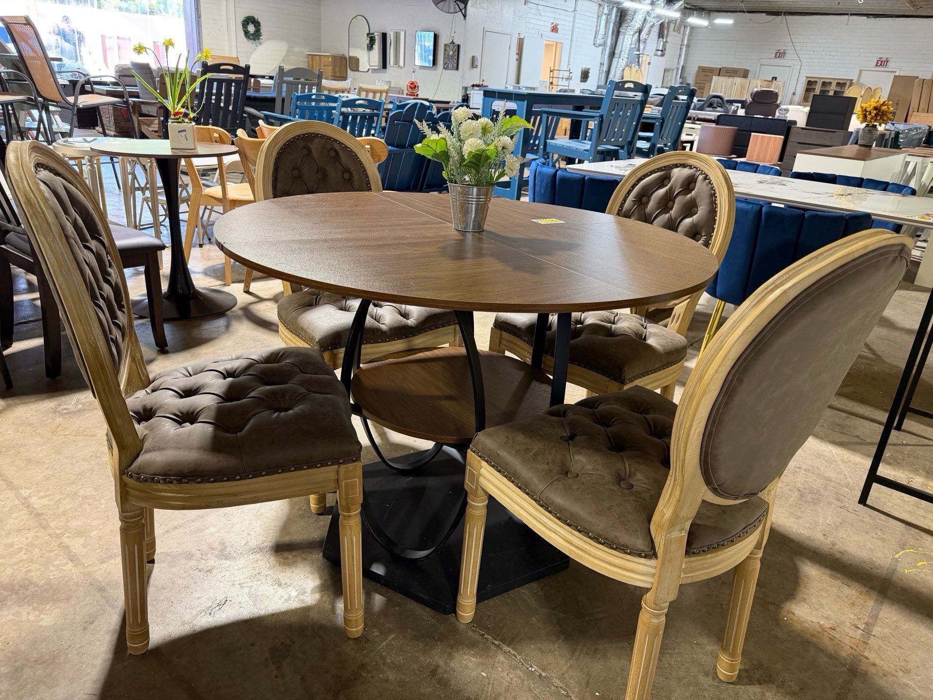 Around Wood table has a cool dark metal base with a lower shelf. Comes with 4 super comfy tufted brown chairs. Light wood frames and nailhead trim loo