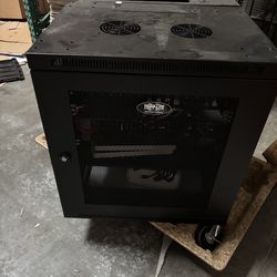 Sturdy Tripp-Lite SmartRack enclosure for your IT setup. Black metal cabinet has a mesh door with a lock. Comes with fans on top and wheels, so it's e