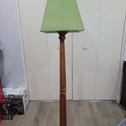This vintage floor lamp features a wooden cherrywood base and a green fabric lampshade.