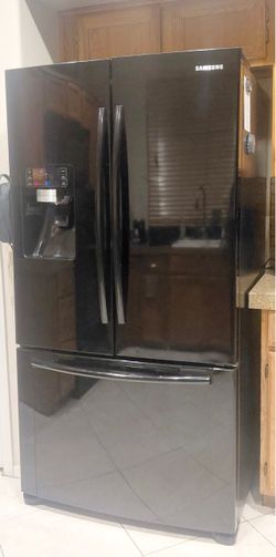Black Samsung French door refrigerator with freezer on bottom with water and ice dispenser.