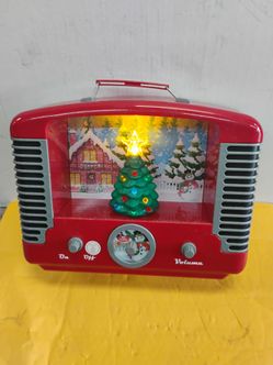 Retro-style Mr. Christmas Nostalgic Holiday Tree Radio featuring an illuminated winter scene and a rotating green Christmas tree inside a red vintage