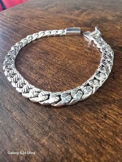silver bracelet featuring a thick, engraved curb-style link design
