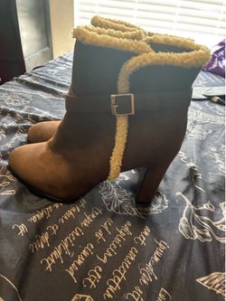 brown ankle boots with a cream shearling lining and a decorative ankle buckle