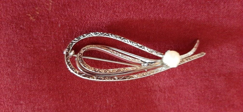 Silver tone brooch with scroll design and pearl.