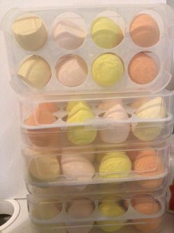 This image shows several sets of makeup sponges, commonly referred to as "beauty eggs," stored in clear plastic containers that resemble egg cartons.