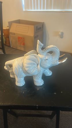 is a vintage Hollywood Regency white glazed ceramic elephant figurine