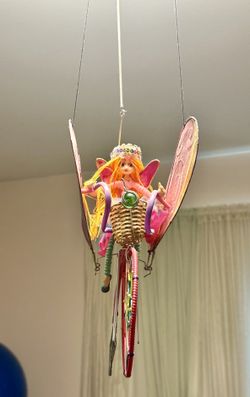 *Whimsical handcrafted decorative fairy w/ bicycle mobile. hanging fairy doll w/ bright yellow hair, wearing a crown, and riding a bicycle that has la