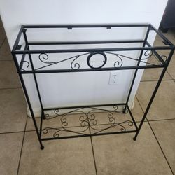 Decorative black metal plant stand with scroll design.