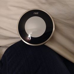 The image shows a Google Nest Learning Thermostat, likely a 2nd generation model. 
It is a smart, Wi-Fi-enabled thermostat that learns user preference