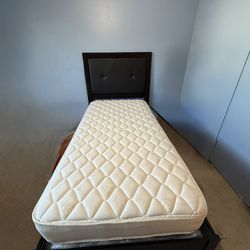 Twin size platform bed frame with upholstered headboard, includes mattress.