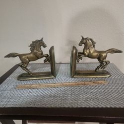Brass bookends of horses jumping over fence