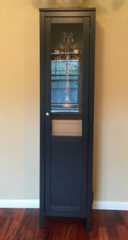Tall black cabinet w/ a partial glass door. Adjustable shelving. Door can be made to open from either side.