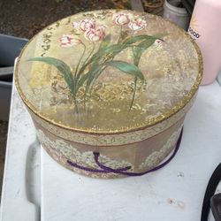 decorative round cardboard hat box featuring a vintage floral design and a purple cord carrying handle. [1] (https://offerup.com/redirect/?o=aHR0cHM6L